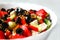 Defocus closeup summer salad. Classic Greek salad from tomatoes, cucumbers, red pepper, onion with olives, oregano and