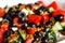 Defocus closeup summer salad. Classic Greek salad from tomatoes, cucumbers, red pepper, onion with olives, oregano and