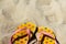 Defocus dirty bright yellow and pink slippers flip flops with pink and blue hearts on the sand. Summer background.The