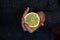 Defocus female hand holding one yellow slice lemon fruit. Hand holds lemon slice on white background. Closeup. Dark gray