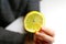 Defocus female hand holding one yellow slice lemon fruit. Hand holds lemon slice on white background. Closeup. Out of