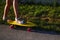 Defocus fit girl in white sandals ready to extreme funny ride her penny board skateboard in sun light. Modern urban