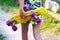 Defocus girl holding yellow penny board. View from back. Summer bright colors. Child hands holding short cruiser