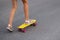 Defocus girl playing on yellow skateboard in the street. Caucasian kid riding penny board, practicing skateboard