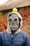 Defocus Halloween people portrait. Person in grim reaper mask standing on nature autumn background holding apple on head