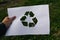 Defocus hand holding cut paper with the logo of green grass nature trash background. Recycling concept. Pollution of the