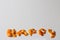 Defocus HAPPY word displayed by orange dry peel on a white background. Happiness concept. Greeting card. Text and DIY