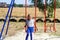 Defocus little girl swinging on swing on playground with. Countryside area. Bright blue and red swing. Kids summer game