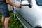 Defocus man washing gray car with sponge on a car wash. Man holds the microfiber in hand and polishes the car. Car