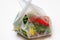 DEFOCUS. Plastic bag. Red and green plants flowers in a plastic bag on a white background. A dry blade of grass sticks