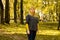 Defocus serious blond 40s woman standing in yellow autumn park. Happy beautiful lady. Women wearing grey pullover