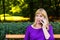 Defocus serious caucasian blond woman talking, speaking on the phone outside, outdoor. 40s years old woman in purple