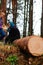 Defocus side view of two woman walking in pine forest and seating on log trunk. Leisure and people concept, mother and