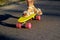 Defocus skater moving along asphalt road on a yellow skateboard wearing white sandals. Some of the legs are on a