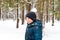 Defocus smiling child boy in winter forest in snowstorm with snowball on head. Funny kid on snowy winter background
