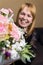 Defocus Smiling woman. Beautiful middle-aged blonde woman feeling excited to receive lovely flower bouquet for spring
