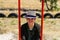 Defocus smiling young woman in checkered shirt and hat swinging on swing on playground. Hipsters and hippie portrait