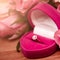 Defocus texture Valentine`s Day background engagement ring with diamonds into a pink heart box