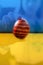 Defocus ukrainian girl in vyshyvanka holding one colored red egg on nature background. Easter, Ukraine flag. Craft