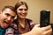 Defocus young man and woman taking selfie. Couple or friends laughing funny and having fun with a smart phone indoors