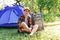 Defocus young woman sitting near camping tent outdoors surrounded by beautiful nature. Freelance, sabbatical, mental