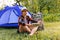 Defocus young woman working on tablet near camping tent outdoors surrounded by beautiful nature. Freelance, sabbatical
