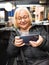 Defocused blonde gamer grandmother playing on smartphone