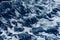 Defocused blue sea water and diagonal wave with white foam and bubbles abstract background. Selective focus