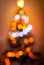 Defocused blurry christmas tree silhouette with blurred lights on warm background.