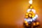 Defocused blurry christmas tree silhouette with blurred lights on warm background and space for your text.