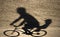 Defocused blurry shadow silhouette of a father riding a bike wit
