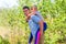 Defocused brother giving sister ride on back in park. Portrait of happy girl on young man shoulders, piggyback. Family playing