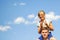 Defocused brother riding sister on back. Portrait of happy girl on man shoulders, piggyback. Girl fly, horns. Family