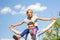 Defocused brother riding sister on back. Portrait of happy girl on man shoulders, piggyback. Girl fly, raise hands. Family playing