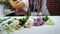 Defocused female florist putting flowers on working table preparing to composition arrangement