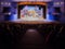Defocused image. Auditorium in the theater during the performance. The scenery on the stage. Adults and children