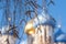 Defocused image of a fragment of an Orthodox church with birch branches in hoarfrost in the foreground.