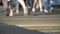 Defocused pedestrians move along yellow and white crosswalk