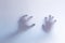 Defocused scary ghost hands behind a white glass background