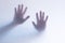 Defocused scary ghost hands behind a white glass background