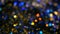 Defocused shimmering multicolored glitter confetti, black background. Holiday abstract festive bokeh light spots.