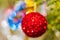 Defocused shining red Christmas ball hanging on branch of Xmas pine tree. Colorful creative abstract blurred bokeh