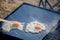 Defocused shot of breakfast camp cooking. Grilling crispy bacon and eggs on a cast iron plate over the camp fire