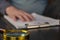 DEFOCUSED SHOT of a hand resting on a clipboard. A gold-rimmed magnifying glass is in the foreground. Adult male laying his hand