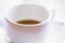 Defocused view of white cup of hot coffee .
