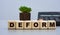 DEFORM - word on wooden cubes against the background of calculator and cactus