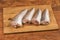 Defrosted raw Argentine hake on cutting board on rustic table