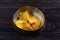 Dehydrated mango slices in a wooden bowl on dark background