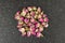 Dehydrated pink rose buds top down view  on a black cutting board