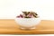 Dehydrated pink rose buds in a white bowl on a wood cutting board